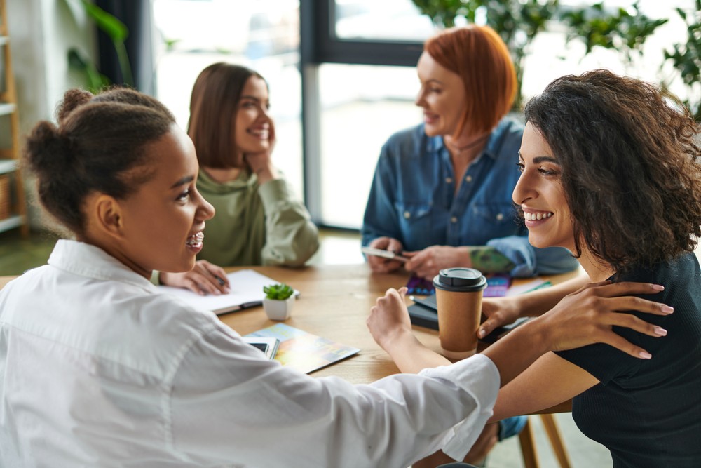 Four women having a friendly conversation in an office, representing the different ways ADHD can affect women.