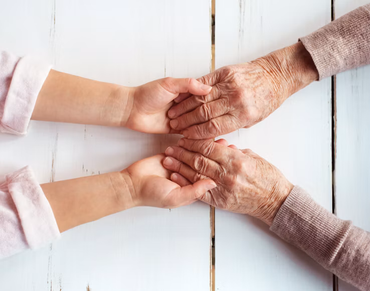 Younger and older adults holding hands, representing support across different life stages.