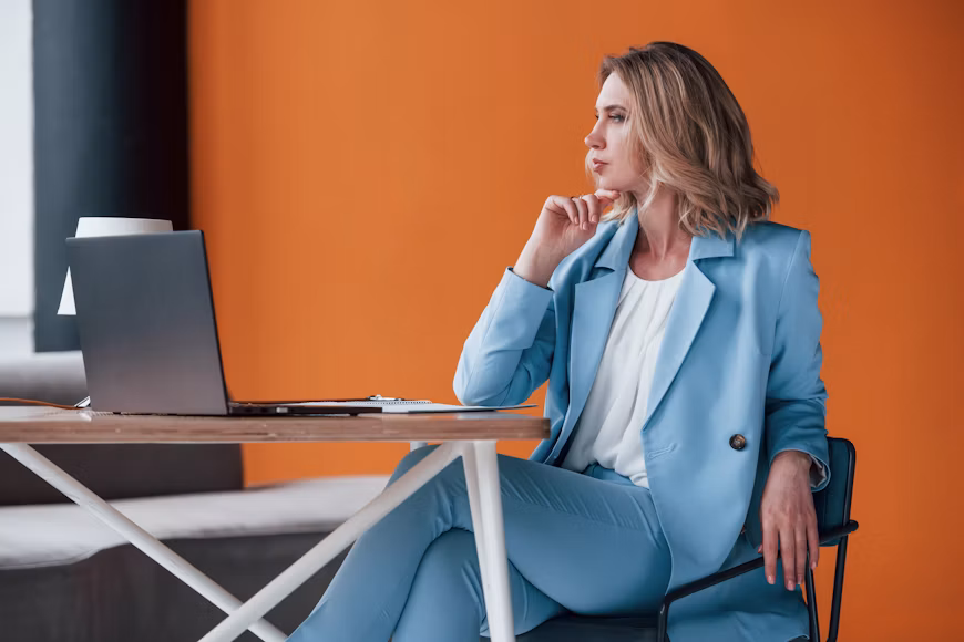 Woman sitting beside a laptop in an office, representing ADHD strategies for work and school.