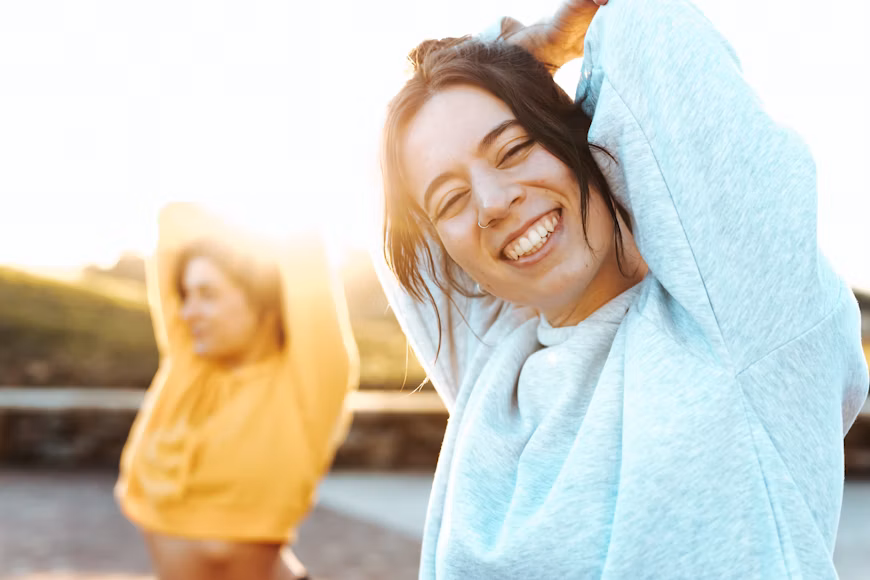 Two women stretching outdoors, representing exercise and healthy living for adults with ADHD.