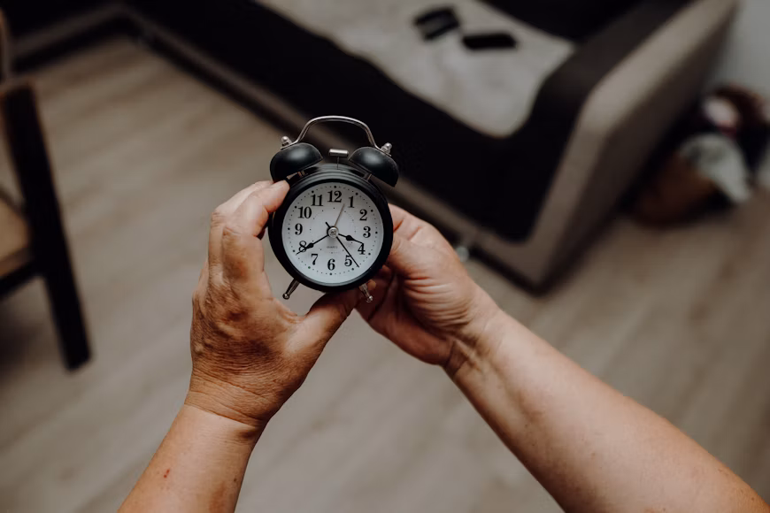 Older adult holding an alarm clock, representing ADHD time blindness and time management challenges.